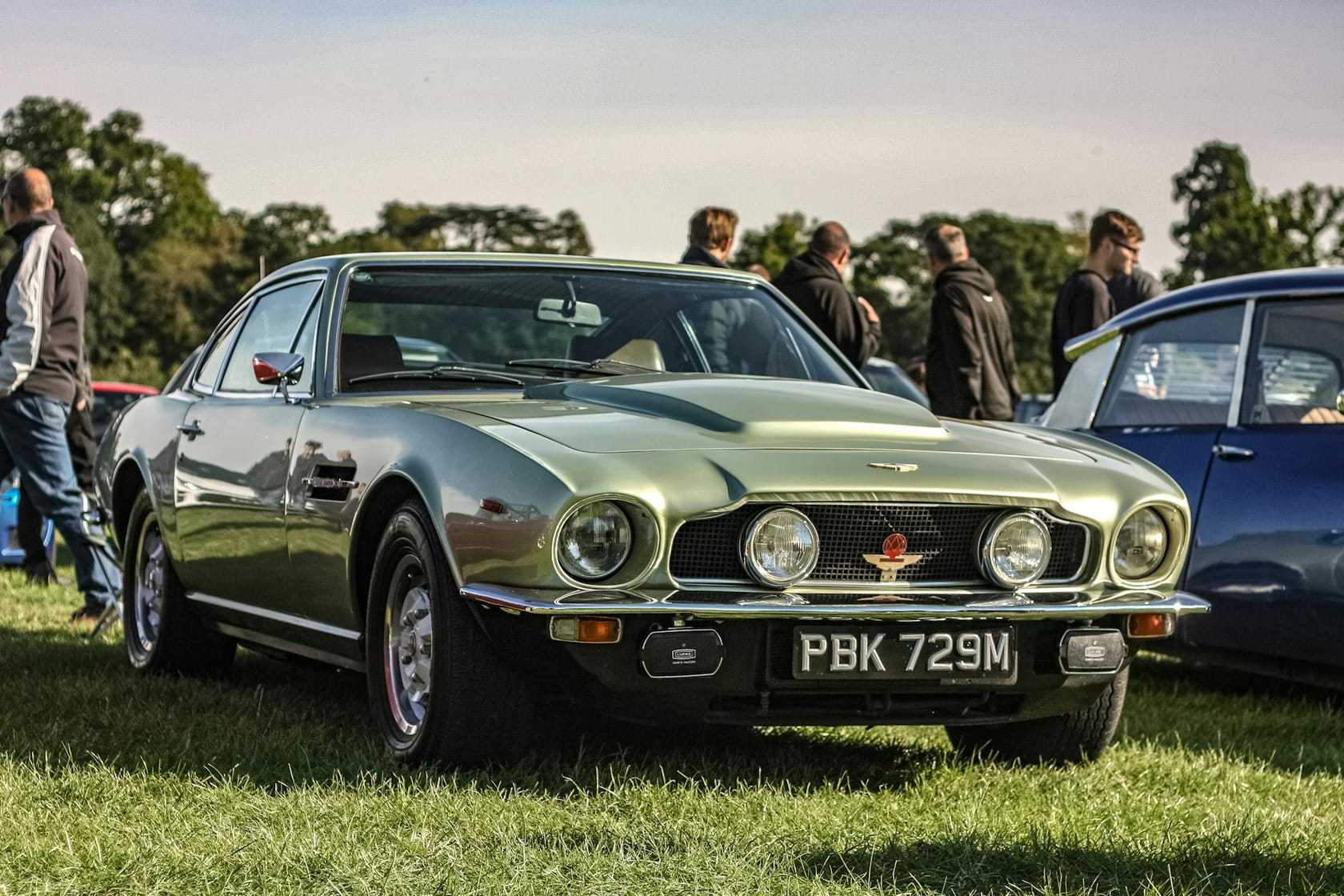 A green Aston Martin V8 with UK registration PBK 729M, front three-quarter view at a classic car show