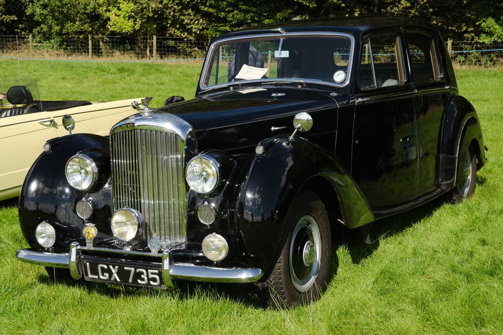 A black 1950 Bentley Mk VI saloon with UK registration LGX 735, front three-quarter view on a lawn