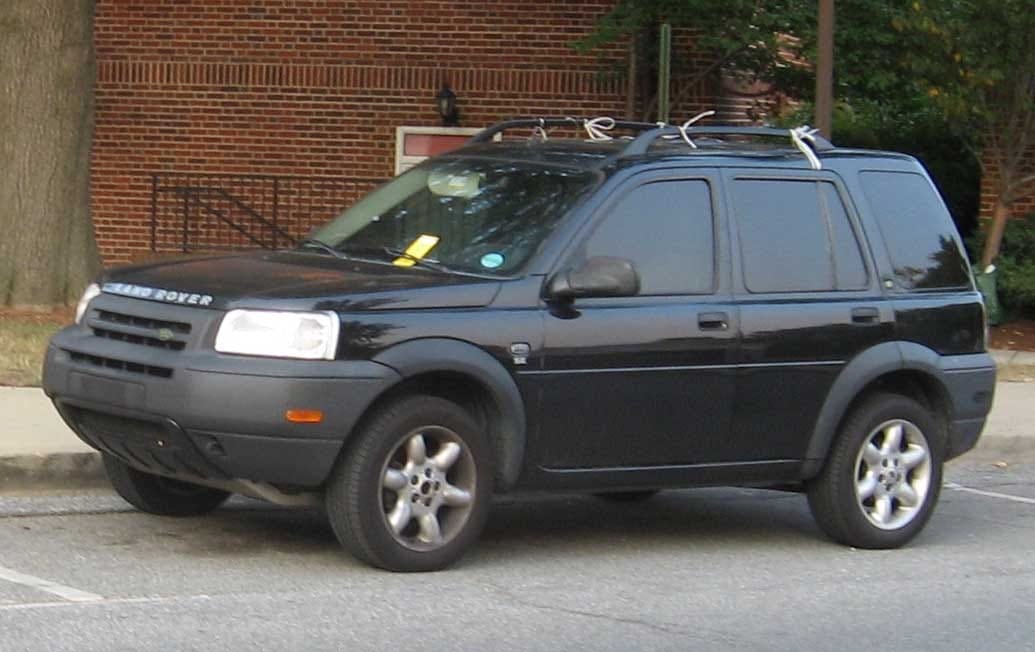 A black pre-facelift Land Rover Freelander five-door parked beside a brick wall