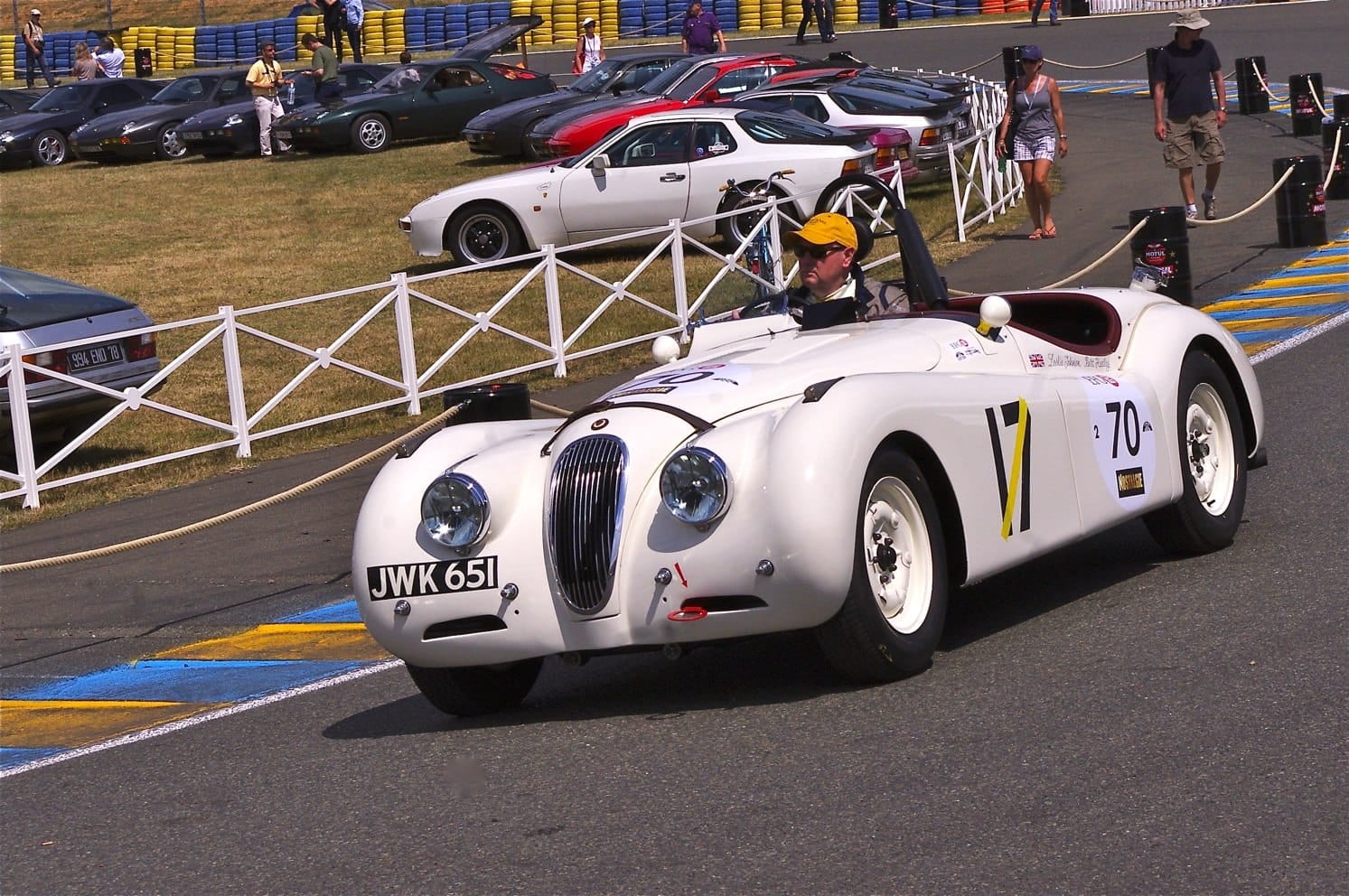 A white 1950 Jaguar XK120 roadster with a UK registration racing at the Le Mans Classic