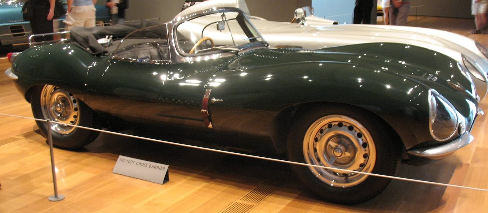 A dark green Jaguar XKSS roadster on museum display, front three-quarter view