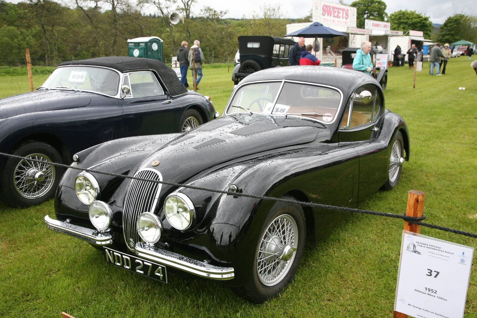 A black 1953 Jaguar XK120 fixed-head coupé with a UK registration and wire wheels on a show field