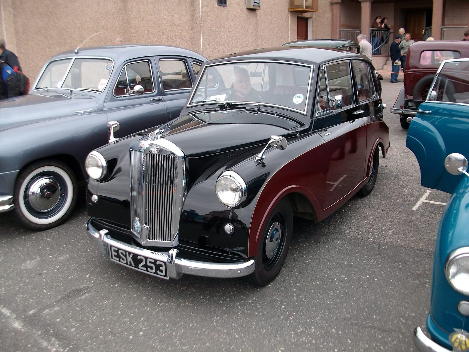 A black over red 1953 Triumph Mayflower with UK registration ESK 253 parked among classic cars