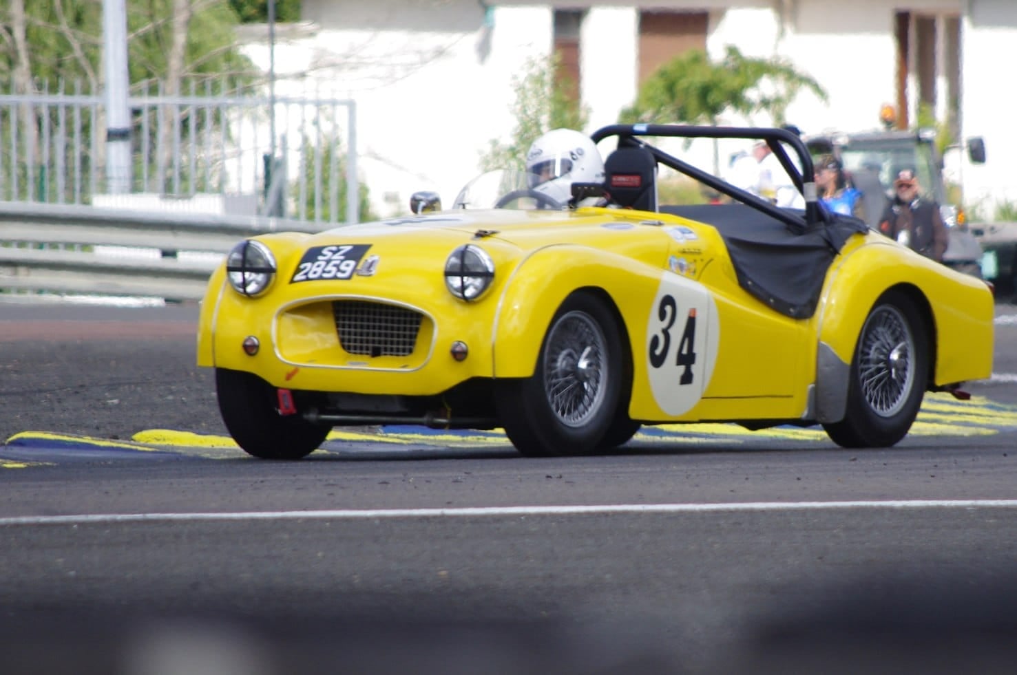 A yellow Triumph TR2 racing car, number 34, on a circuit