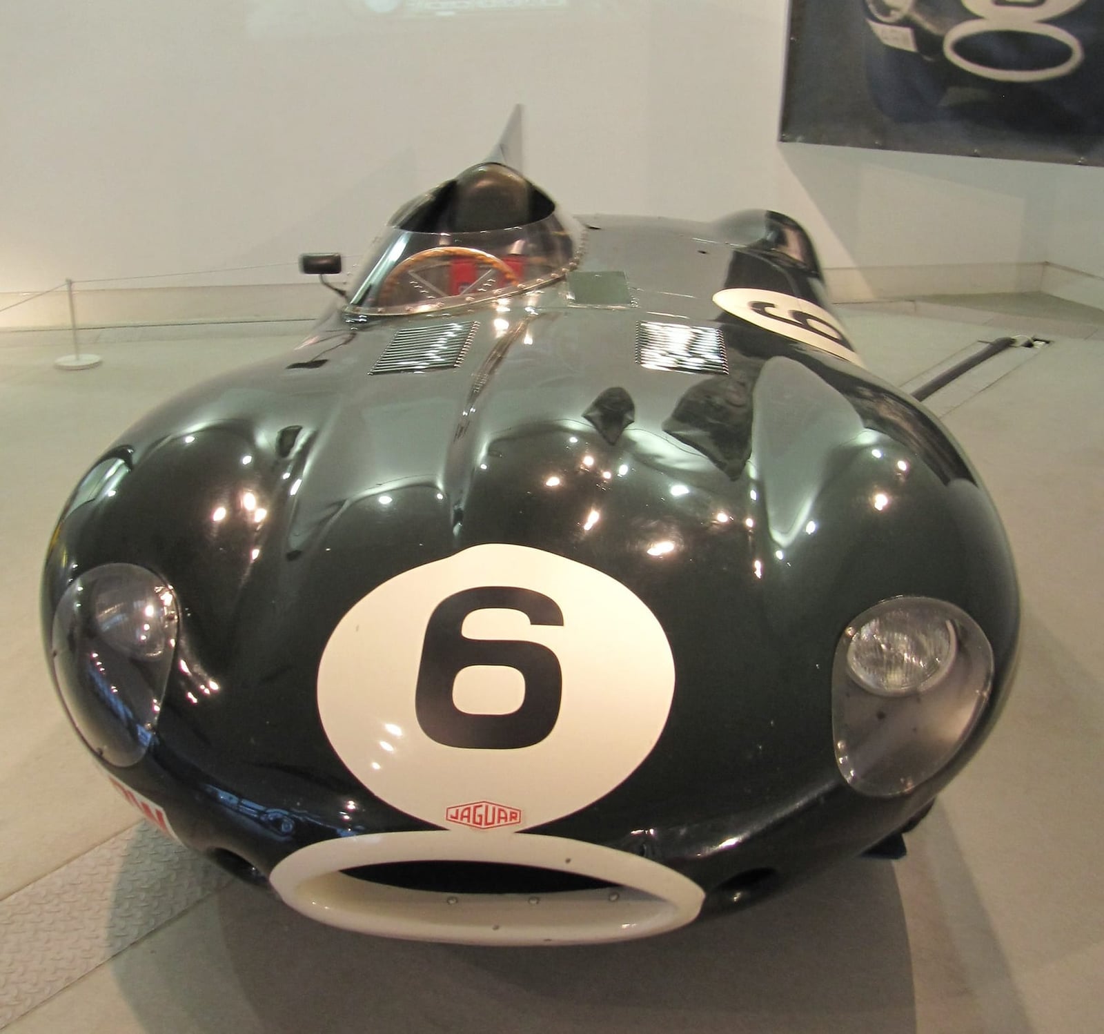 A green Jaguar D-Type racing number 6 with tail fin, front view on museum display