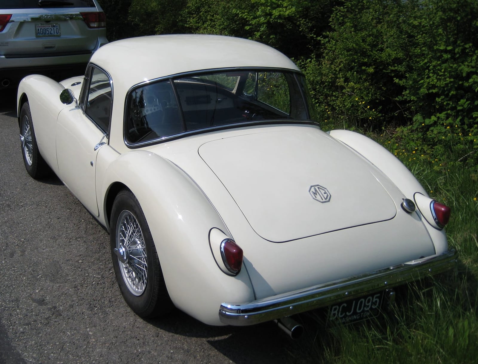 The rear of a white 1958 MGA fixed-head coupé parked on a street