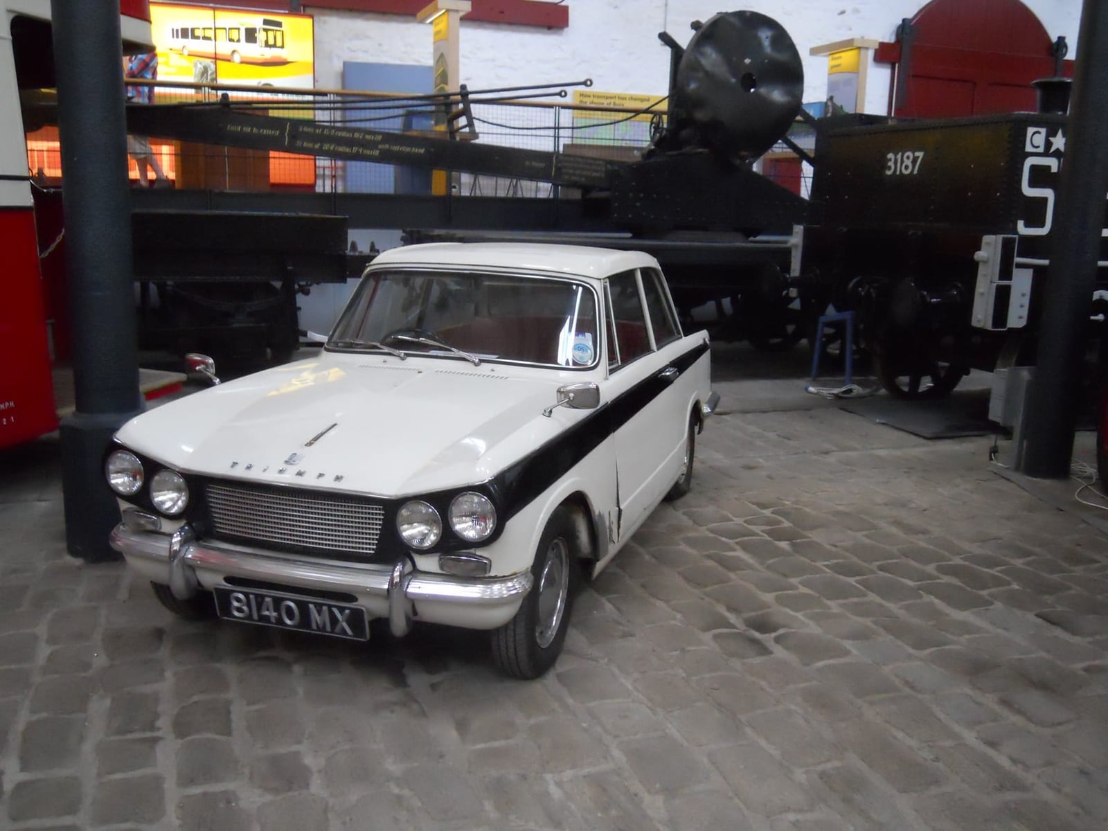 An early two-tone Triumph Herald saloon on display in a transport museum
