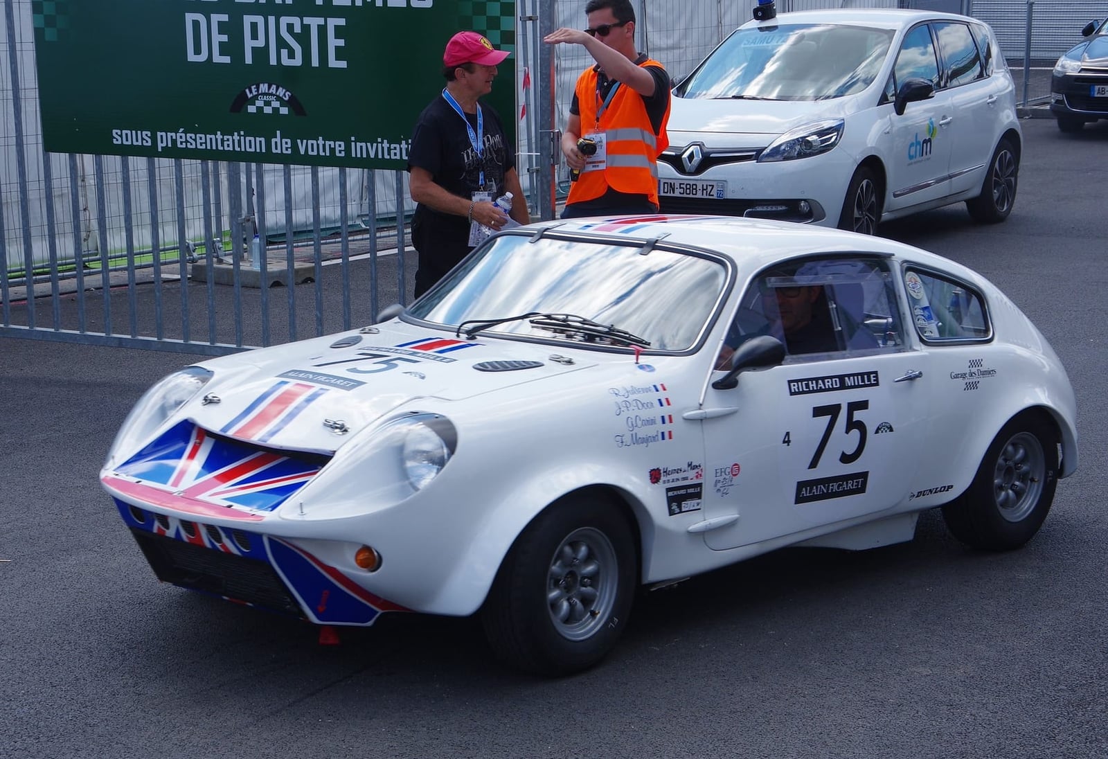 A white Mini Marcos in period racing trim with a competition number and a Union Jack on the nose