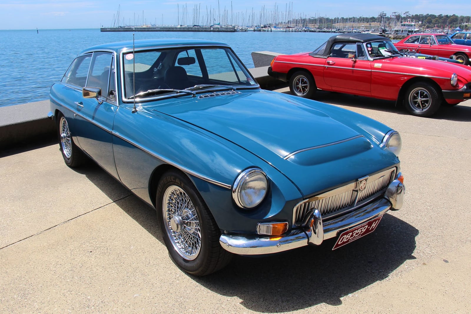A blue MG MGC GT by the sea, front three-quarter view