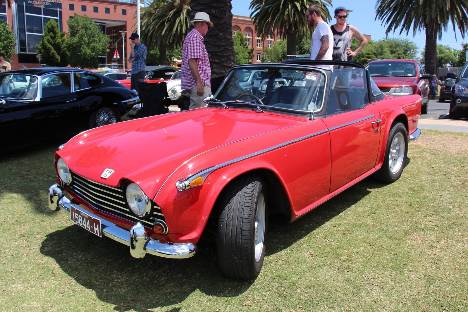 A red Triumph TR5 roadster with the hood down at a classic-car show