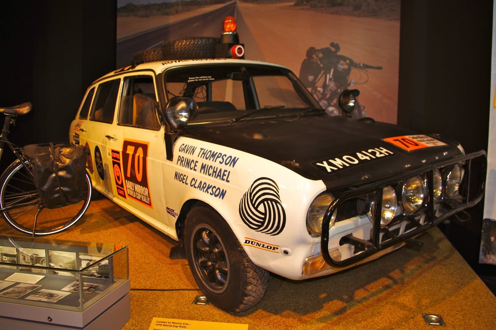 A red and white 1970 Austin Maxi in World Cup Rally livery displayed in a museum