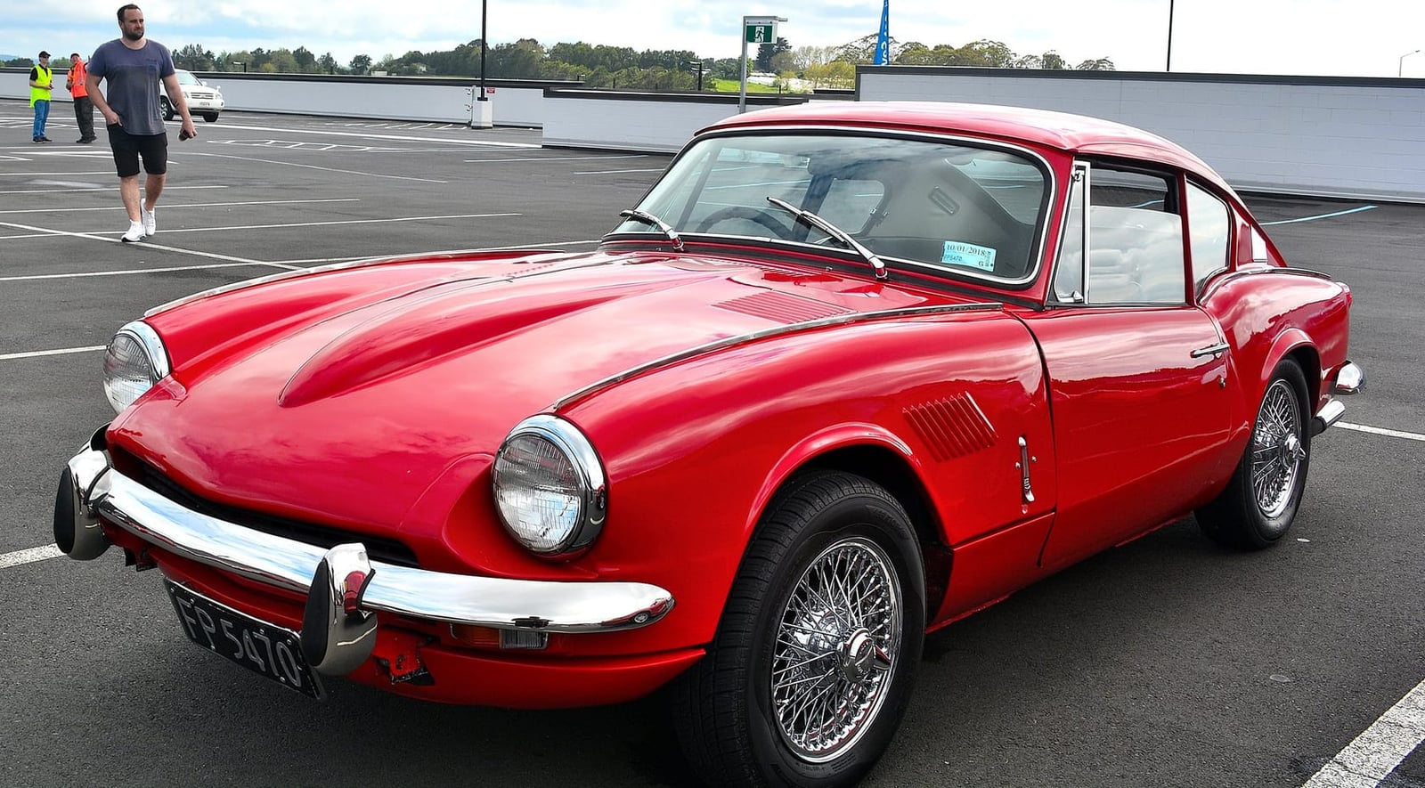 A red Triumph GT6 Mk2, front three-quarter view on a road