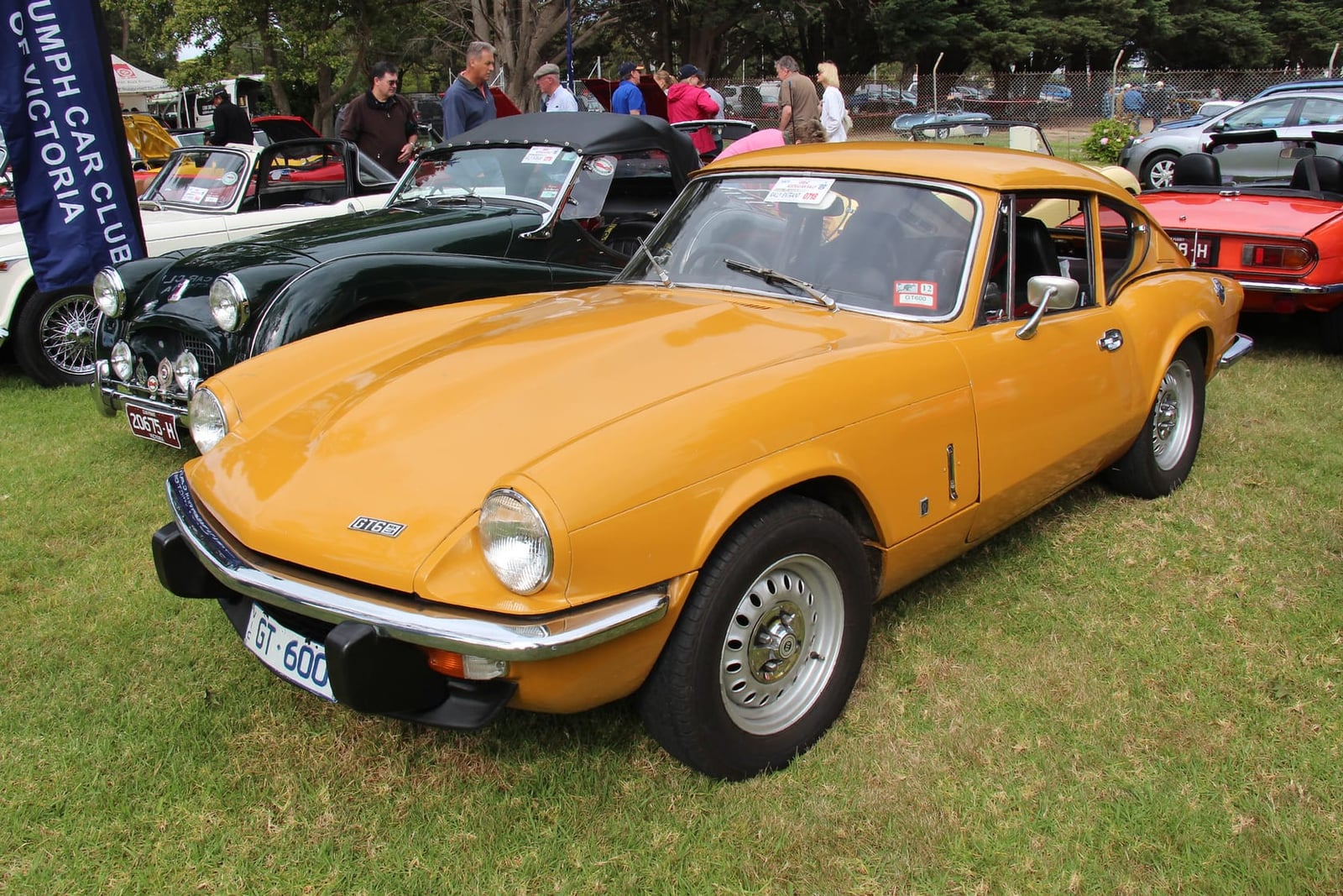 A red Triumph GT6 Mk3 fastback coupe, front three-quarter view at a show