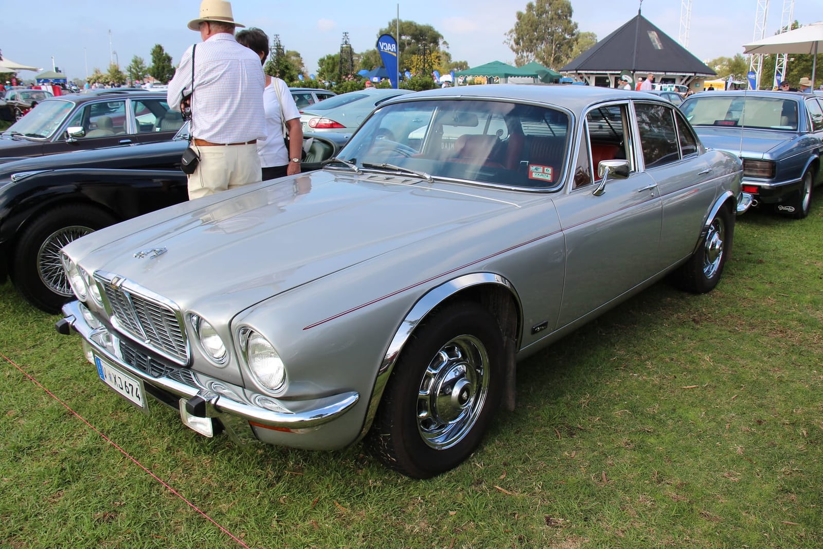 A silver 1975 Jaguar XJ6 Series 2 saloon on grass at a classic car show, front three-quarter view