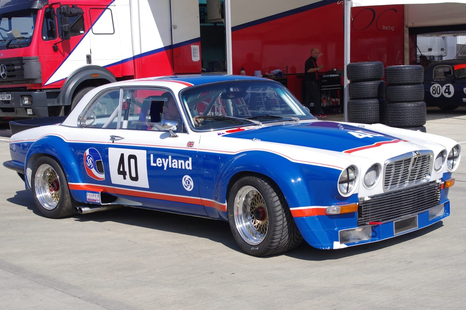 A white, red and blue Broadspeed Jaguar XJ12 coupe racing car in Leyland livery, number 40, in a race paddock