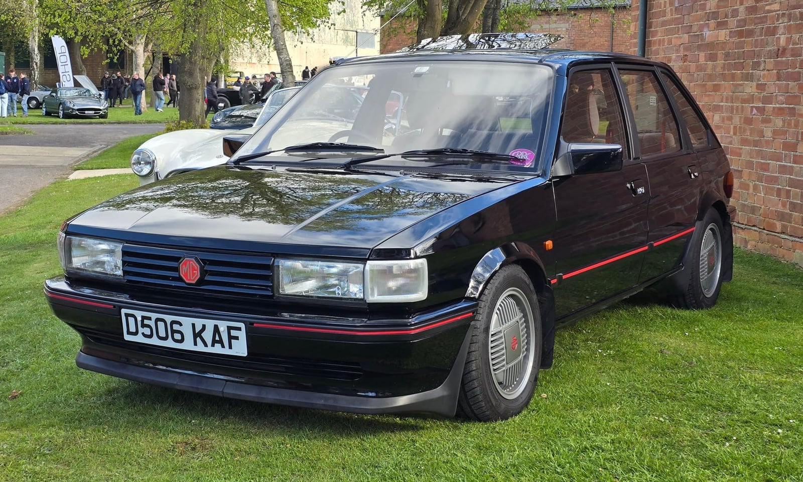 A black 1986 MG Maestro 2.0 EFi with red pinstripes and a UK registration on grass at a show