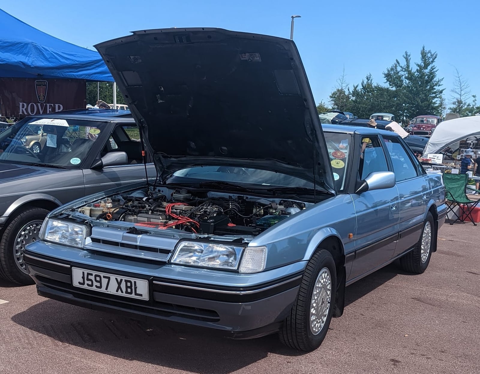 A light blue 1992 Rover 827 SLi with its bonnet raised at a show, the Honda V6 engine visible