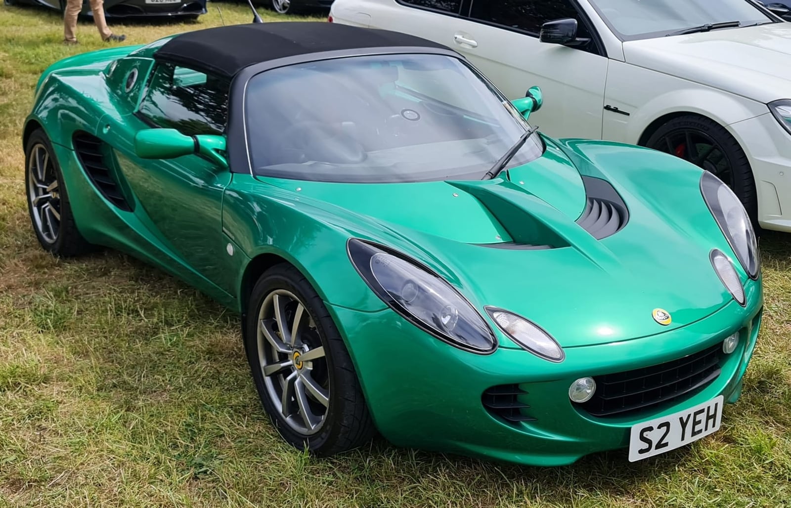 A metallic green 2002 Lotus Elise S2 111S with a UK registration on a show field