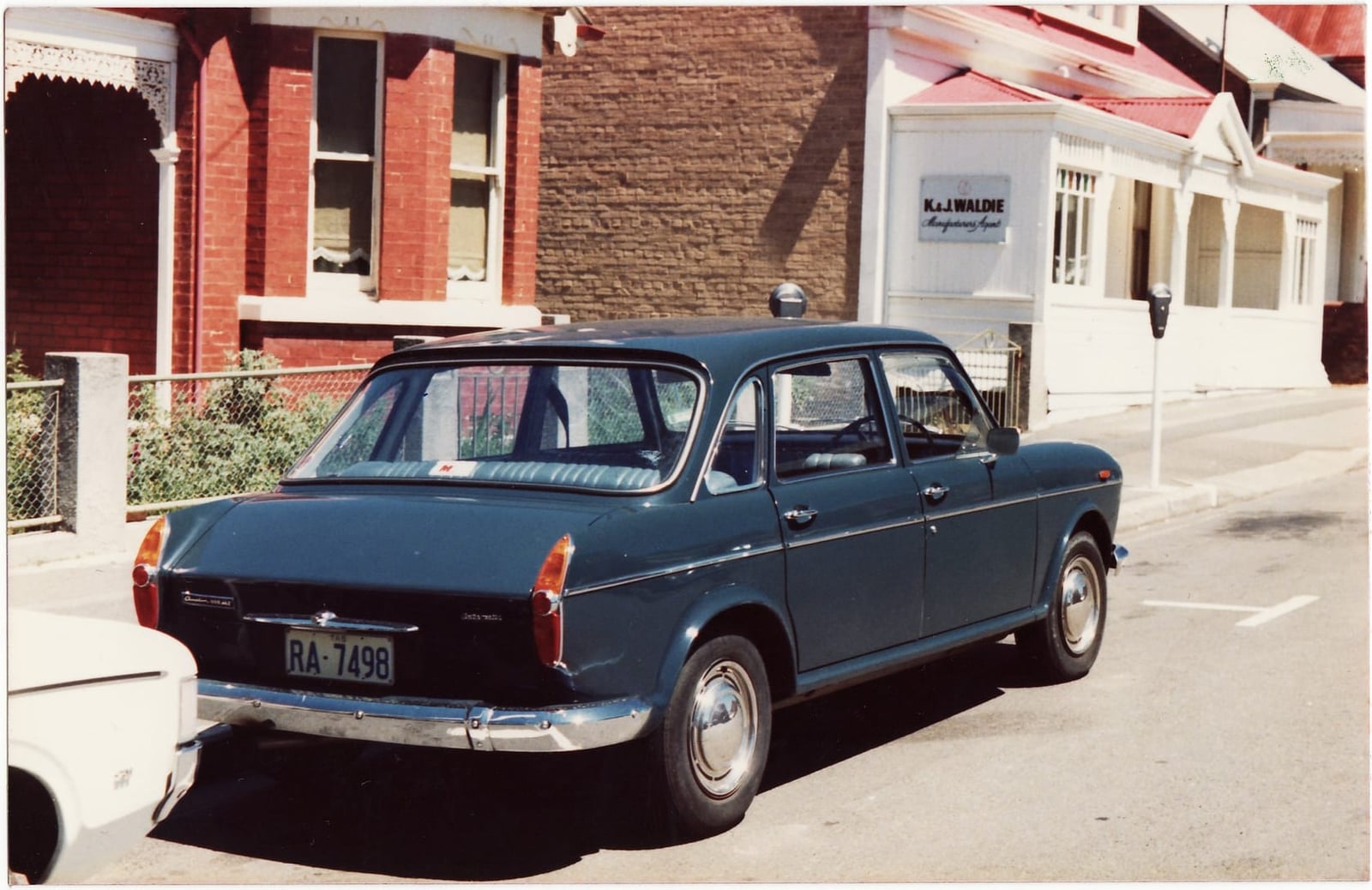 A blue Austin 1800 Mk II photographed from the rear three-quarter on a period street