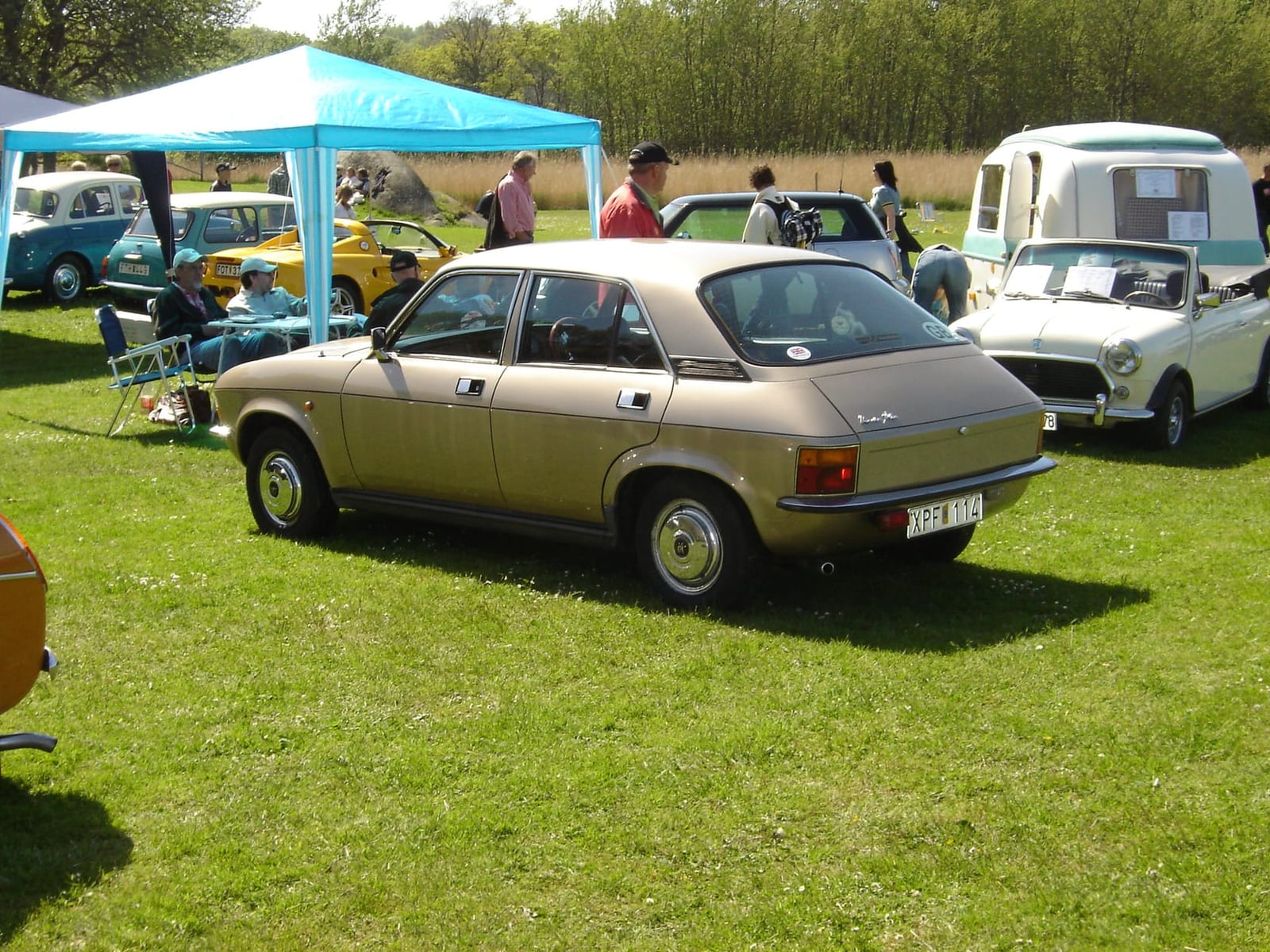 A gold Austin Allegro four-door saloon, rear three-quarter view, parked on grass at a classic-car show