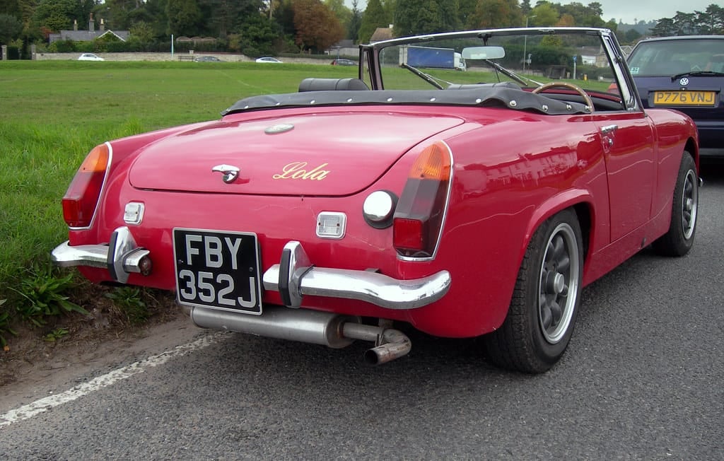 The rear of a red 1971 Austin-Healey Sprite Mk IV with a UK registration parked on a verge