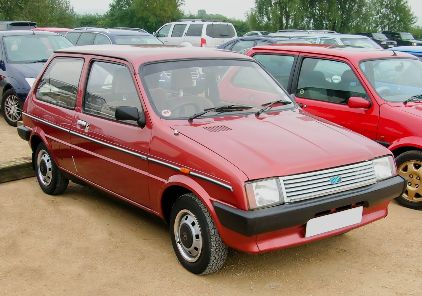 A red 1983 Austin Metro automatic parked at a classic car gathering, front three-quarter view