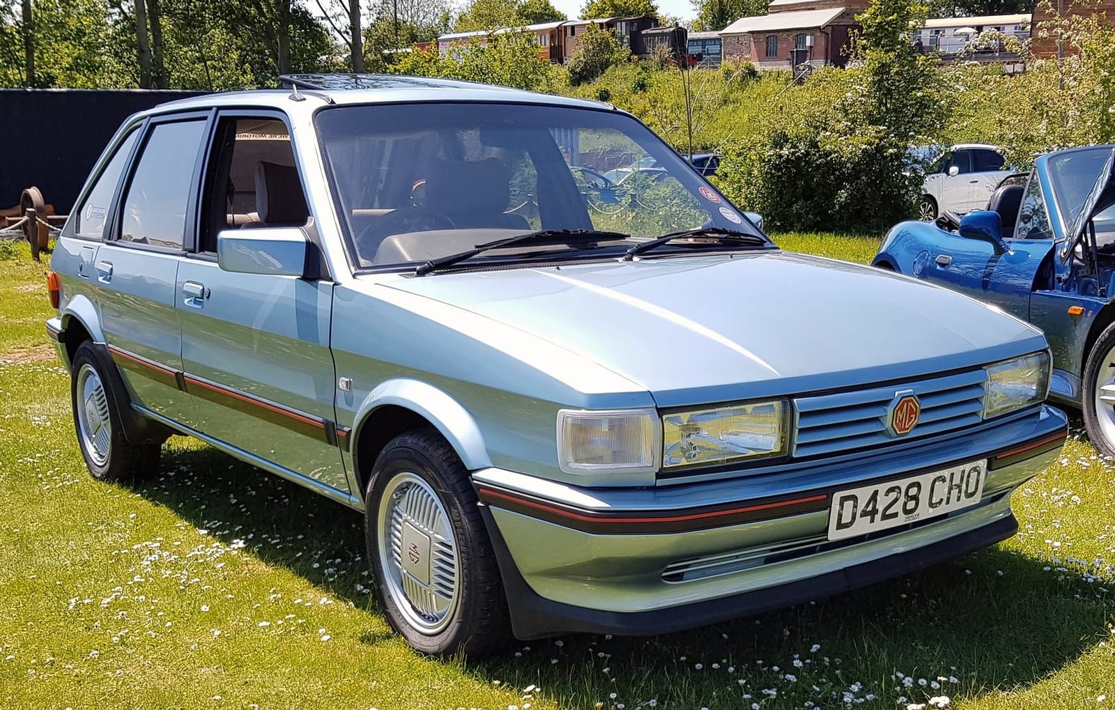 A silver-blue MG Maestro with a UK registration on a show field