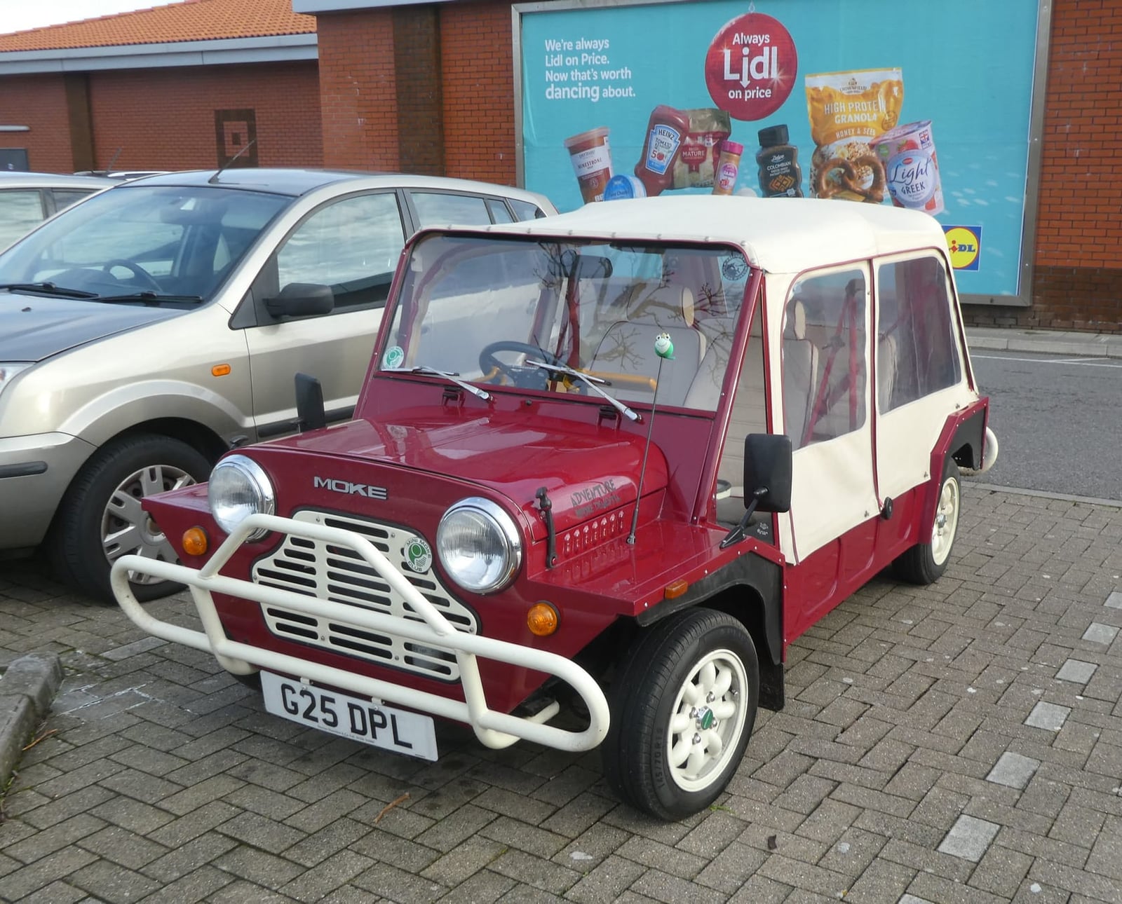 A red Mini Moke with a white top, front three-quarter view