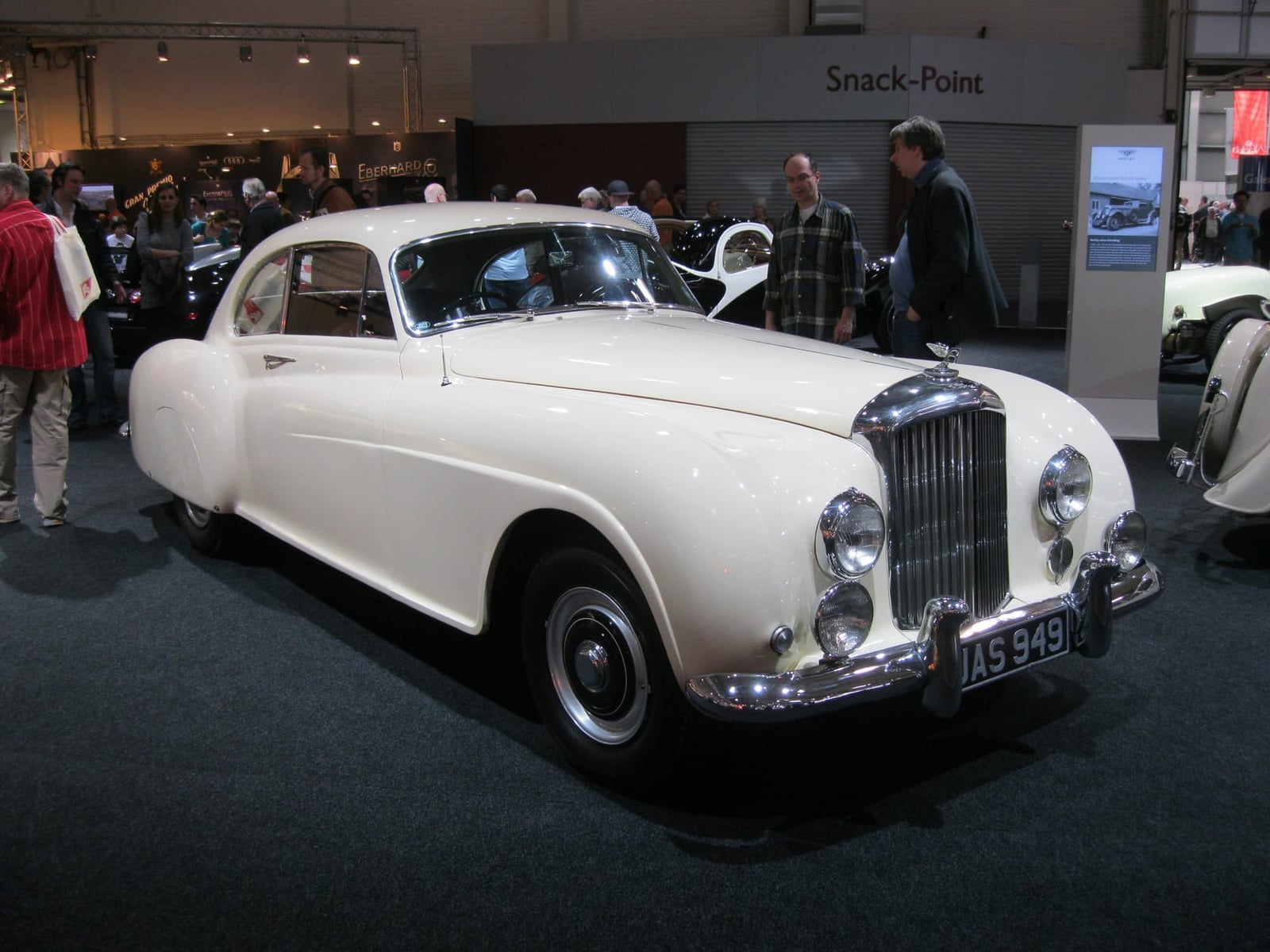 A white Bentley R Type Continental fastback displayed at an indoor show