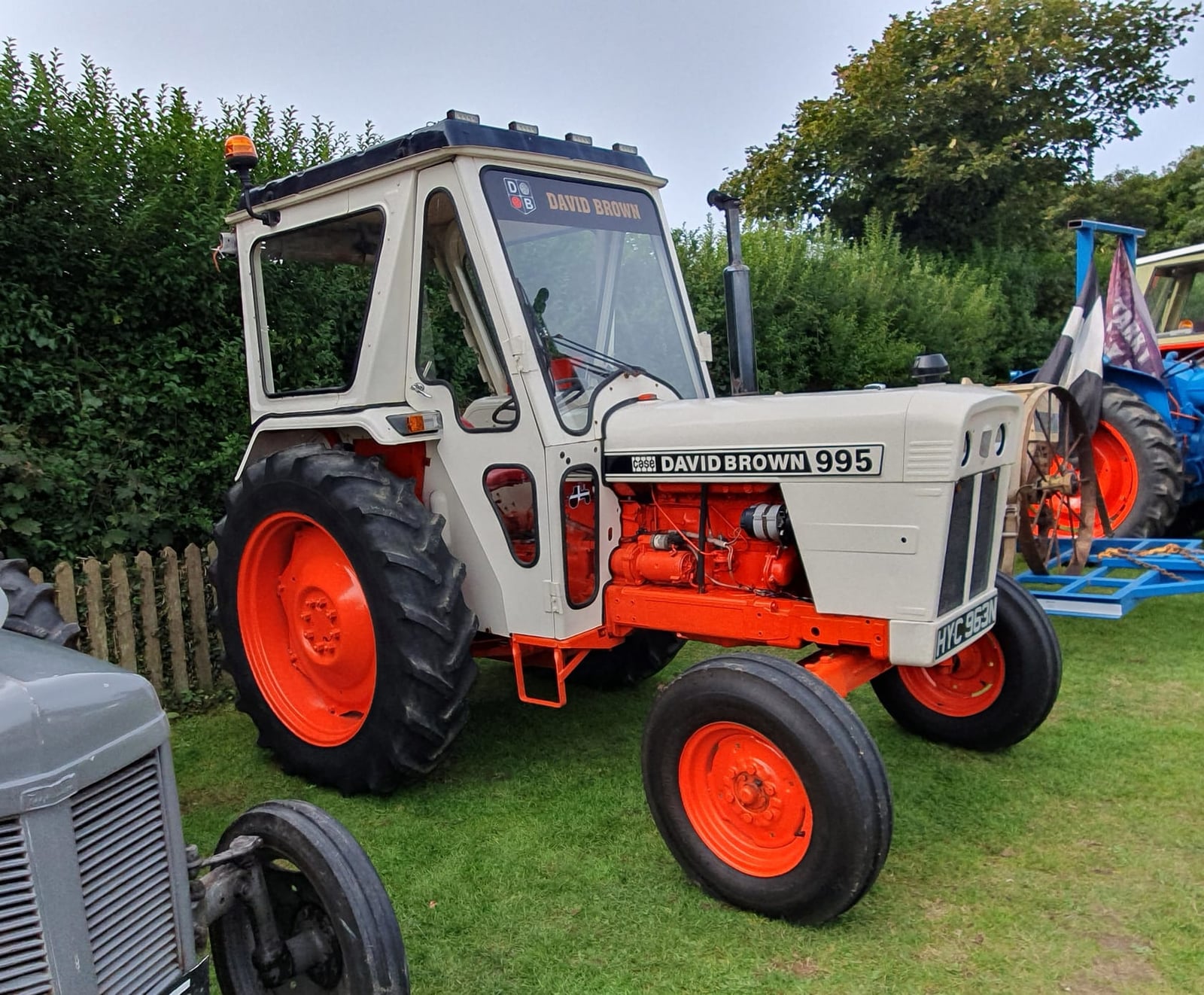 A white and orange David Brown 995 with cab at a Cornish vintage rally