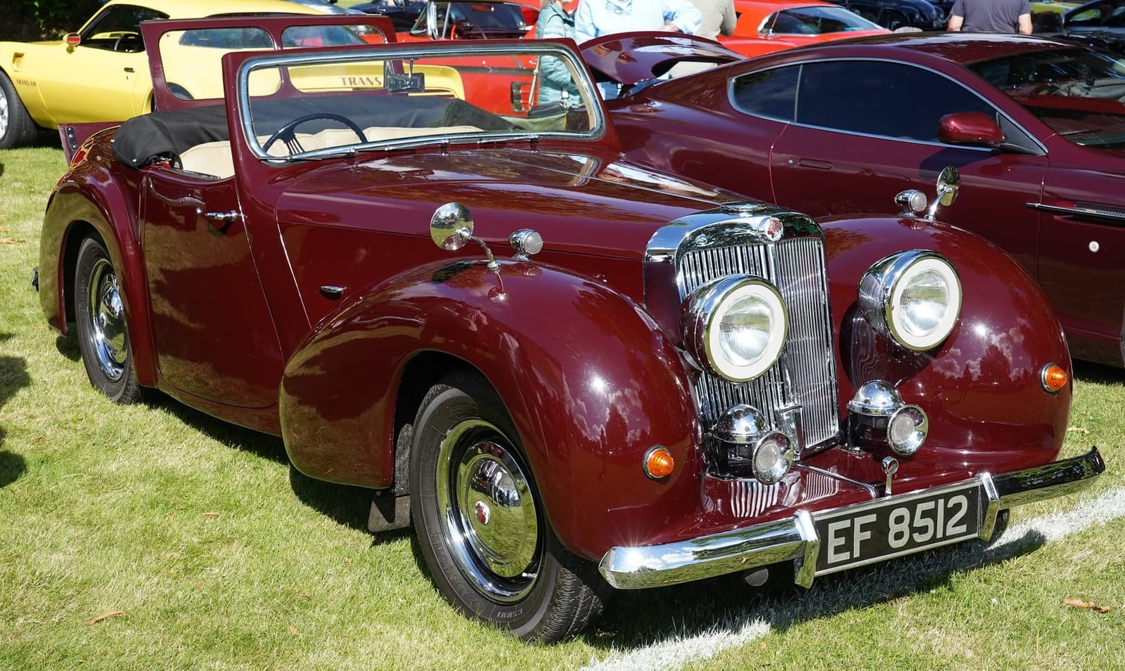 A maroon 1948 Triumph 1800 Roadster with registration EF 8512 at an outdoor classic car show