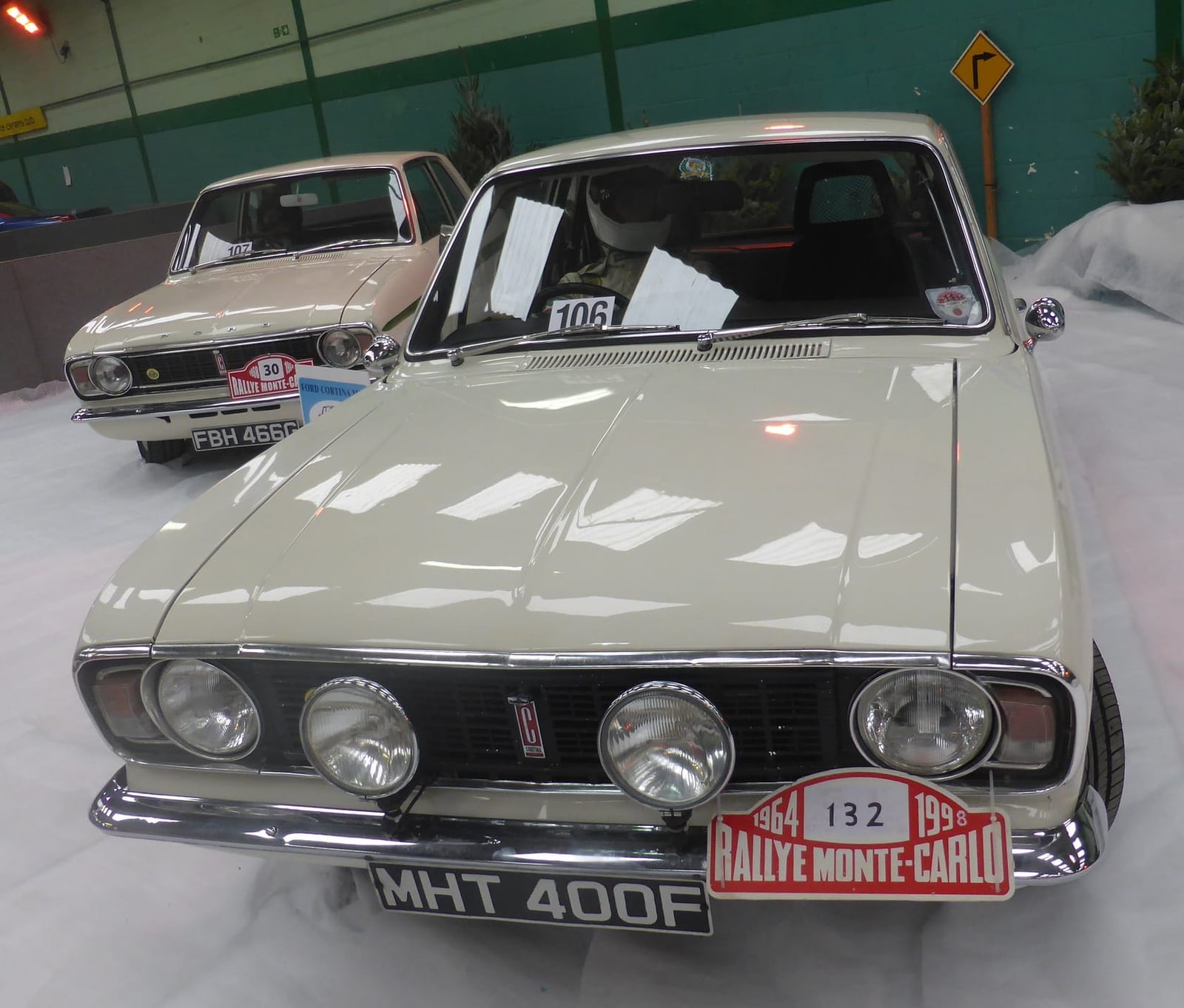 A white Lotus Cortina Mk2 in Monte Carlo Rally competition trim with lamp pod and rally plate number 132, on museum display, UK registration MHT 400F