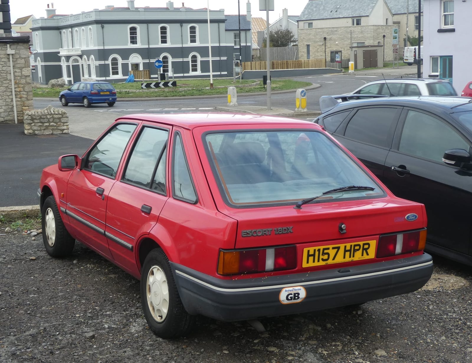 A red 1990 Ford Escort 1.8 DX five-door hatchback, rear three-quarter view on a UK street