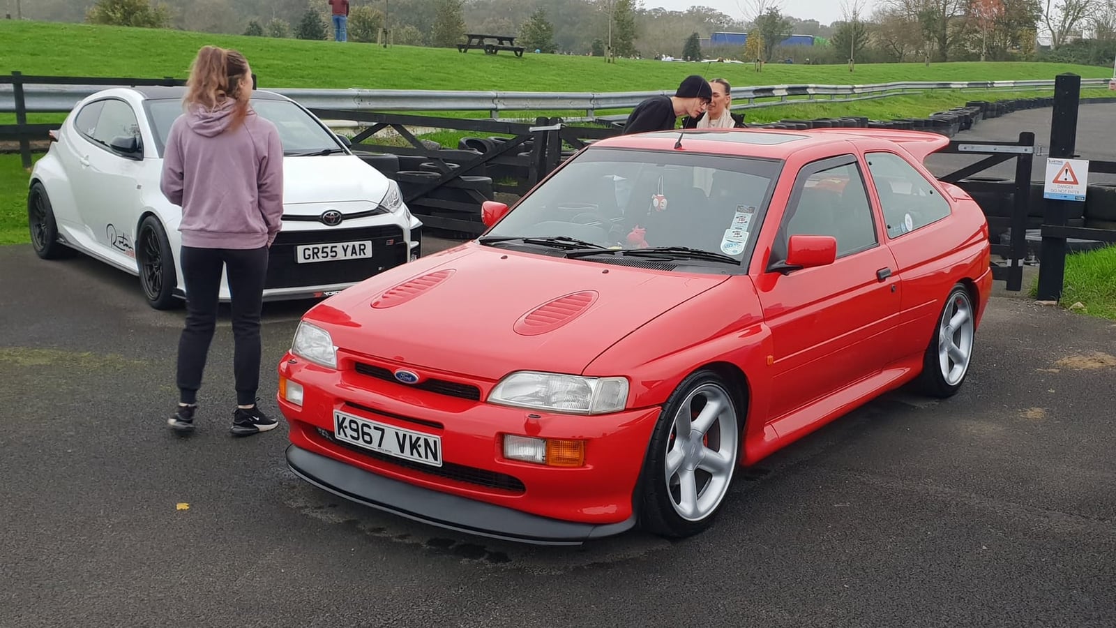 A red 1993 Ford Escort RS Cosworth parked at a circuit, front three-quarter view, UK registration K597 VKN