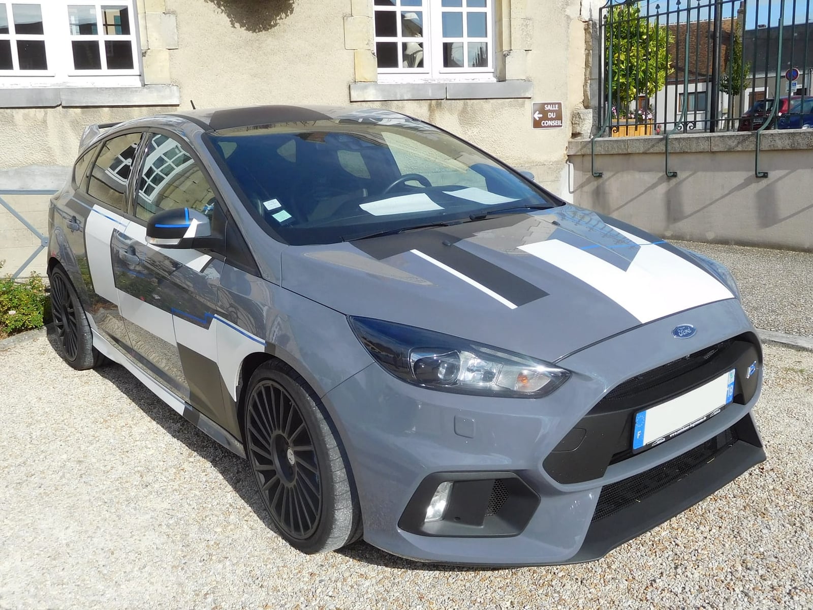 A grey 2016 Ford Focus RS Mk3 five-door parked on gravel beside a stone building