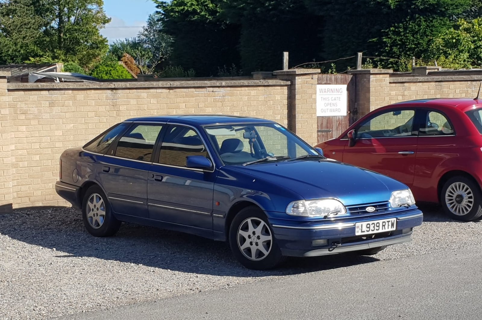 A blue 1993 Ford Granada 2.0 five-door hatchback parked by a brick wall, front three-quarter view