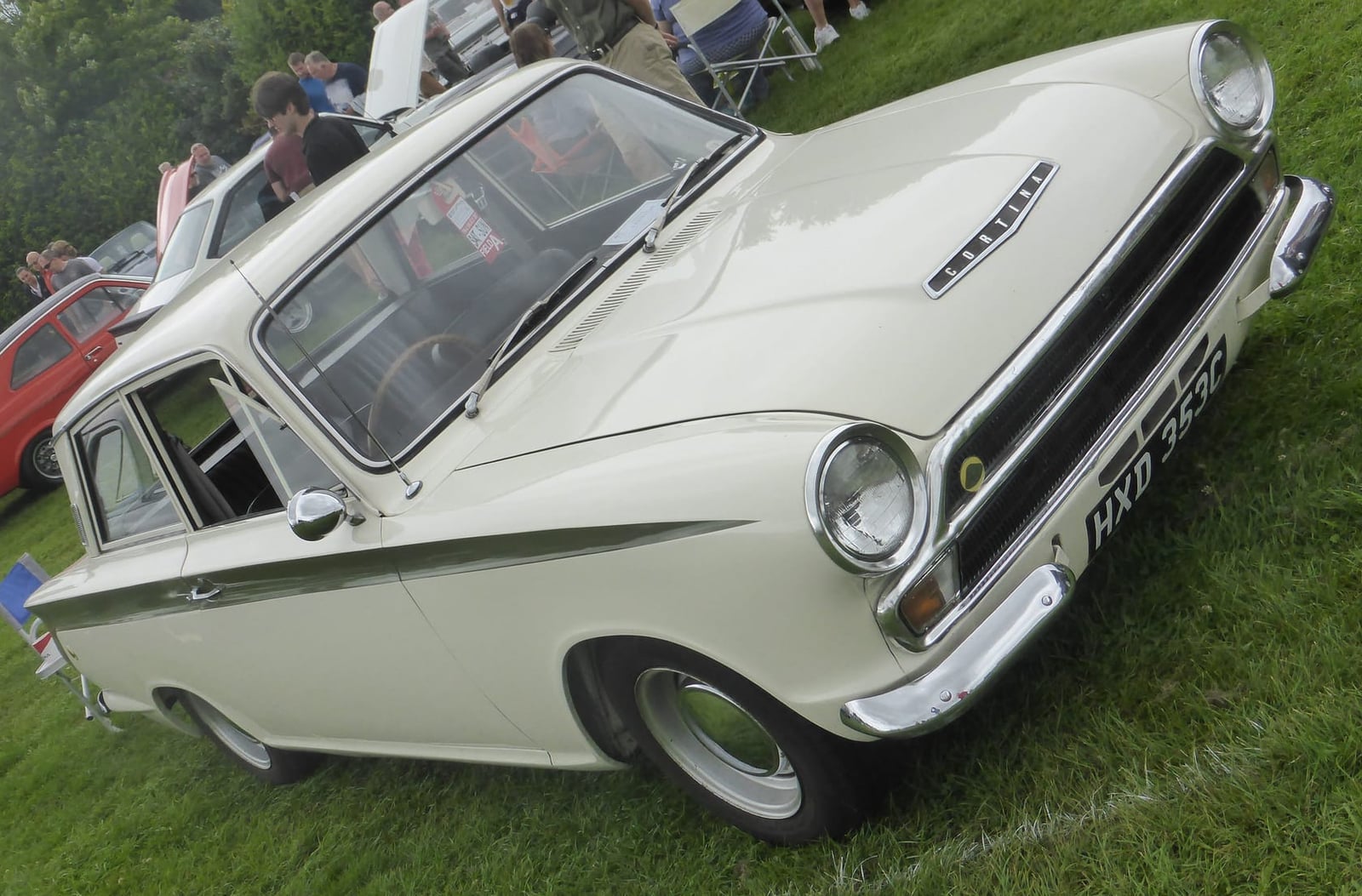 A white Lotus Cortina Mk1 with green flash at a classic car show, front three-quarter view, UK registration MXD 355C