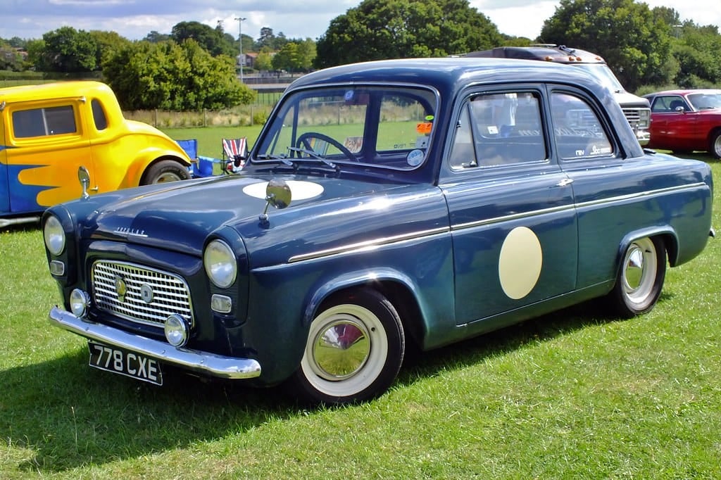 A dark blue Ford Prefect 100E prepared for competition with a cream roundel on the door, on grass at a show, UK registration 278 CXE