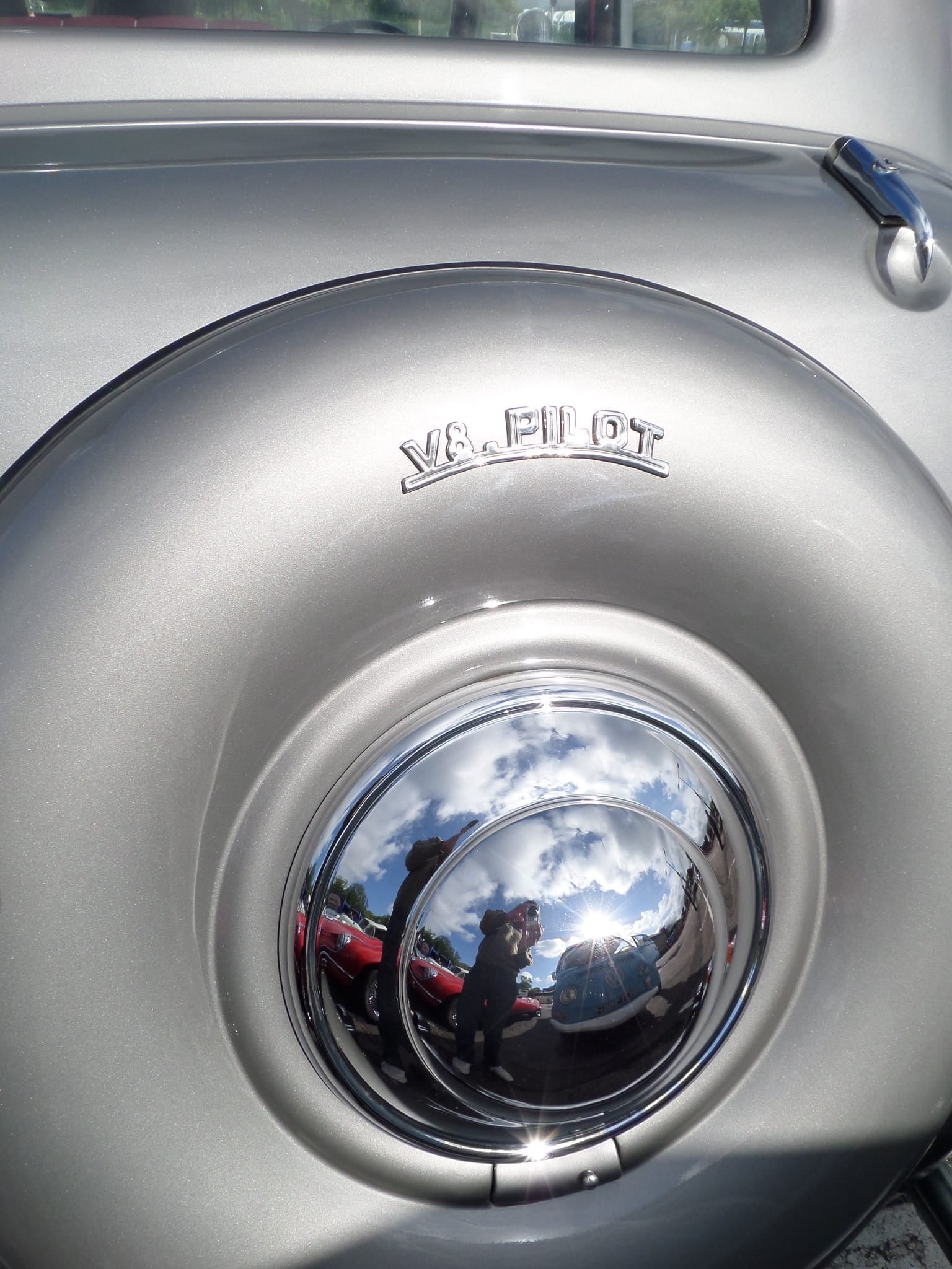 Close-up of a Ford V8 Pilot hubcap and V8 Pilot script on grey bodywork