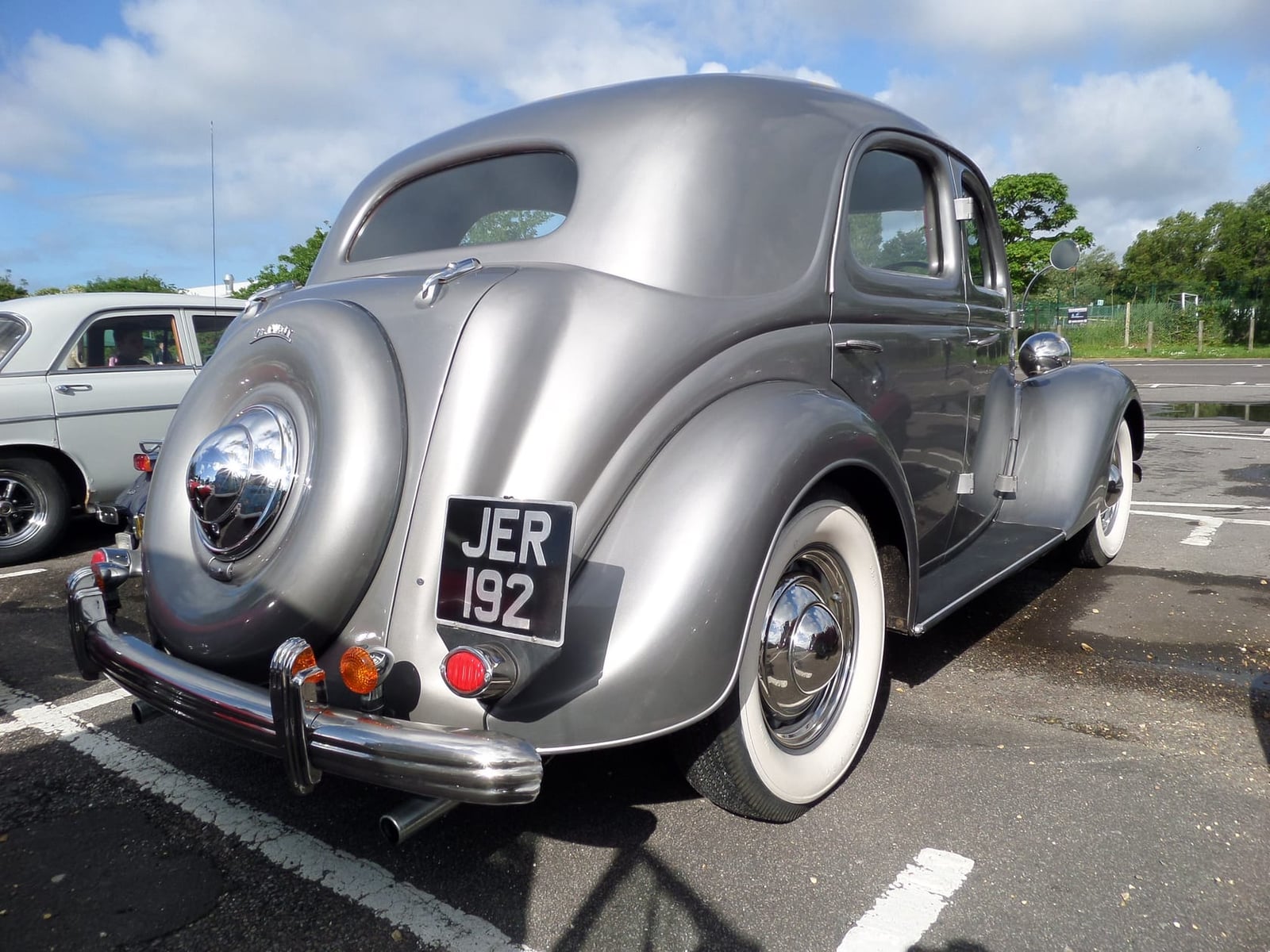 A silver Ford V8 Pilot photographed from the rear three-quarter at a classic car meet, UK registration JER 192