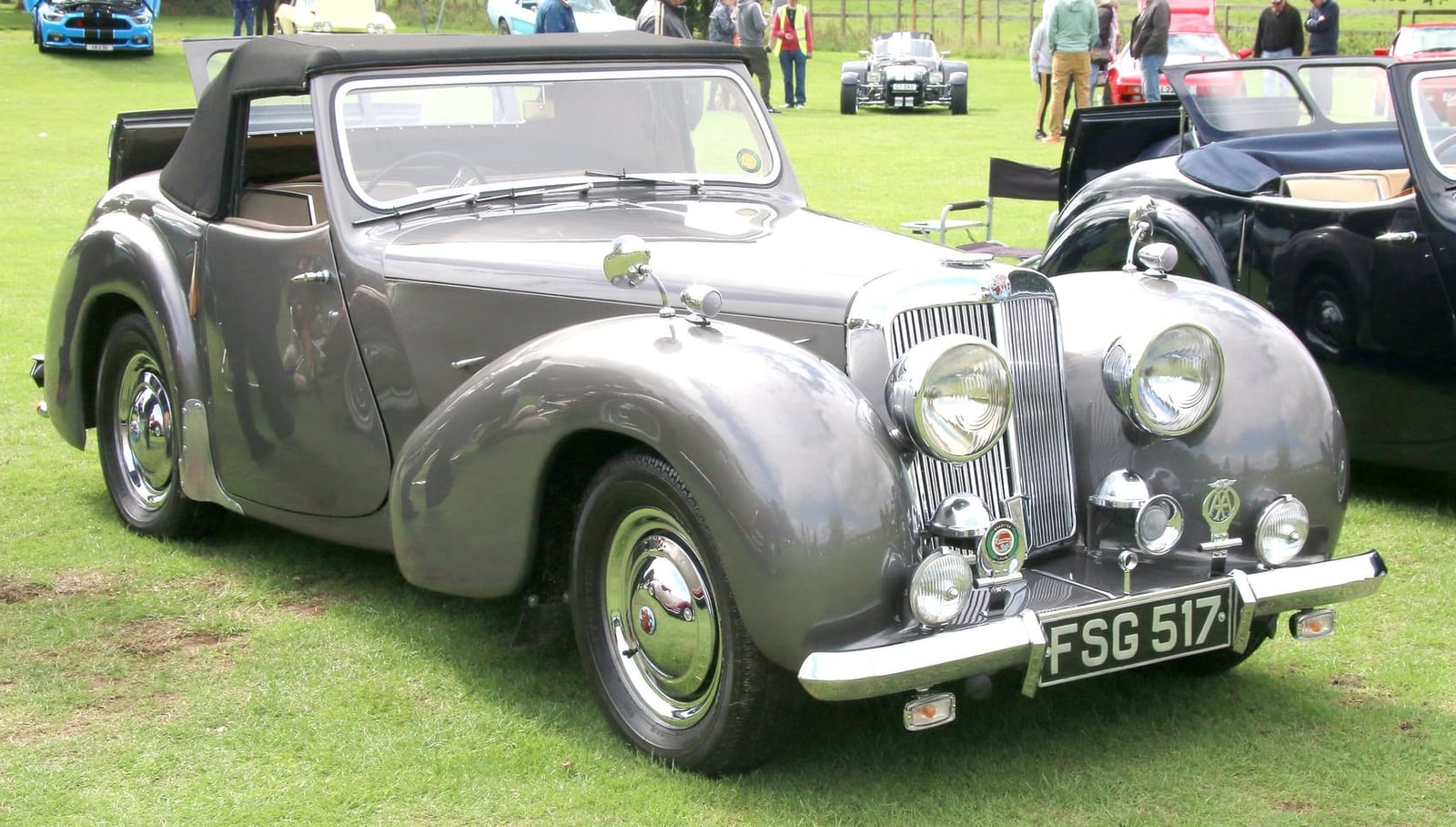 A silver-grey 1948 Triumph 1800 Roadster displayed on grass at a classic car show