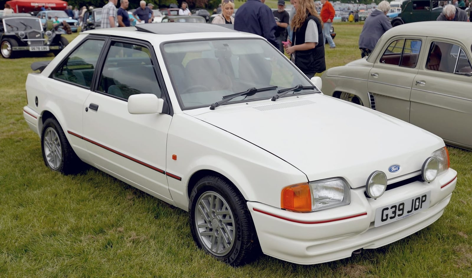 A white Ford Escort XR3i hatchback, front three-quarter view at a show