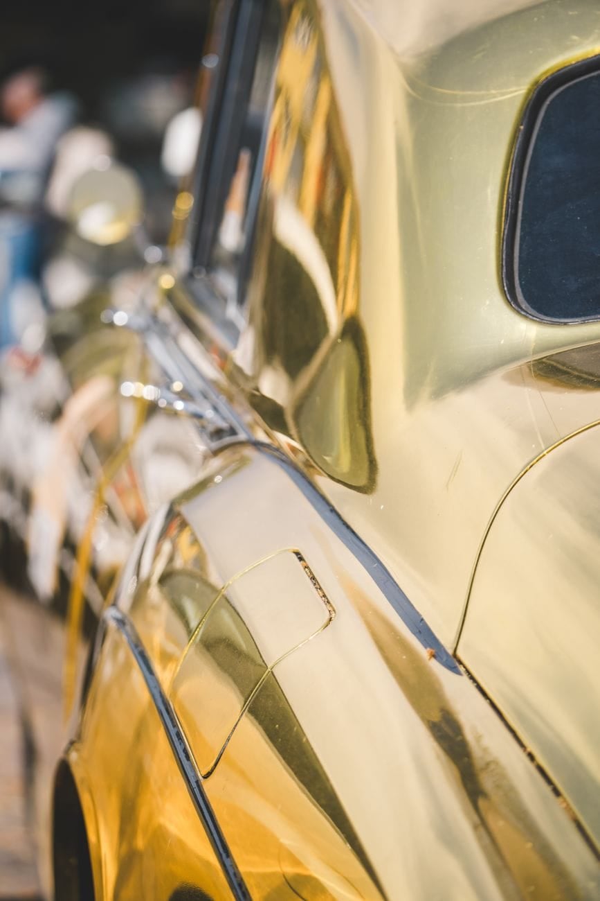 A close detail of the wing and bonnet of a gold Rolls-Royce Silver Cloud