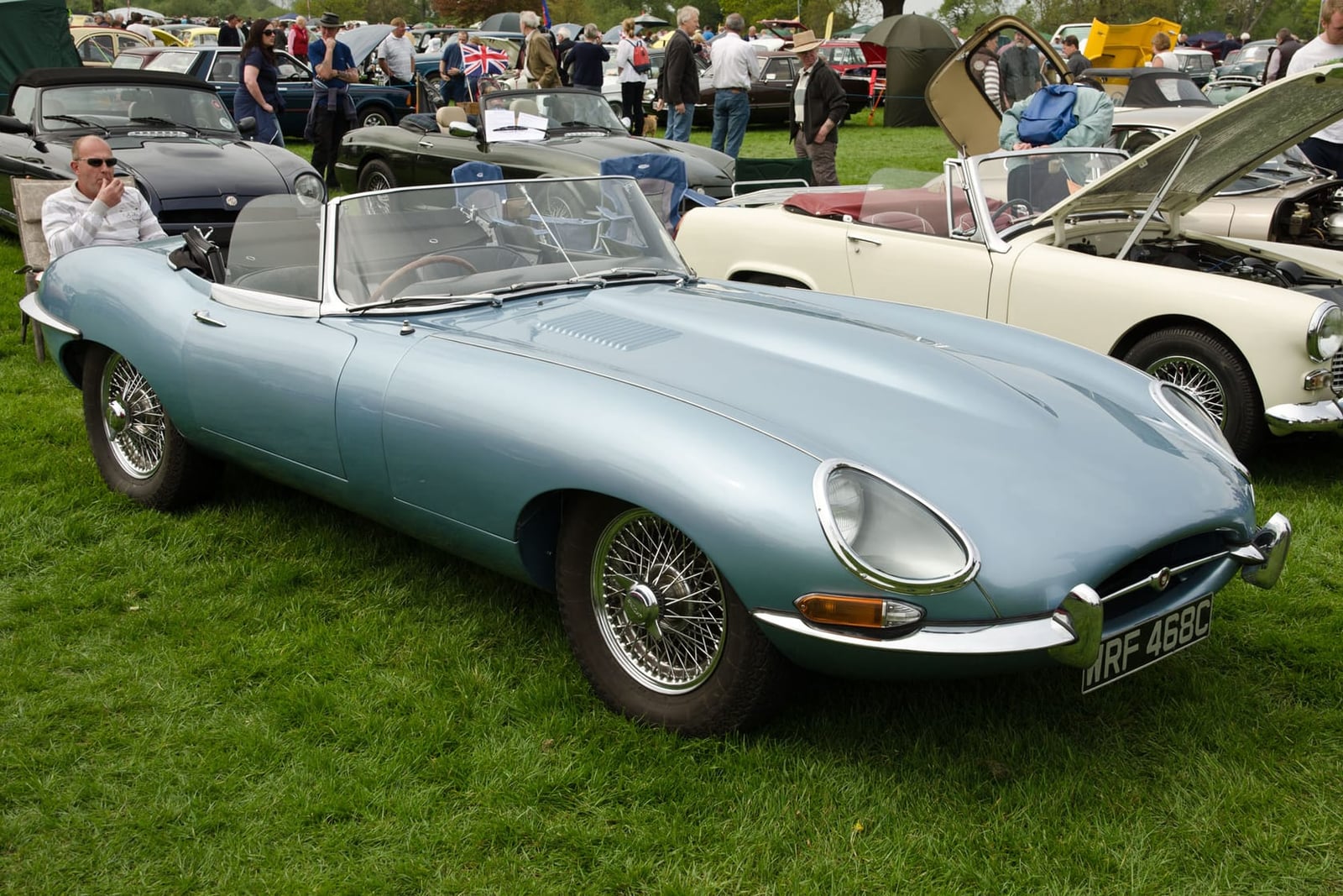 An opalescent blue 1965 Jaguar E-Type Series 1 roadster at a classic car show