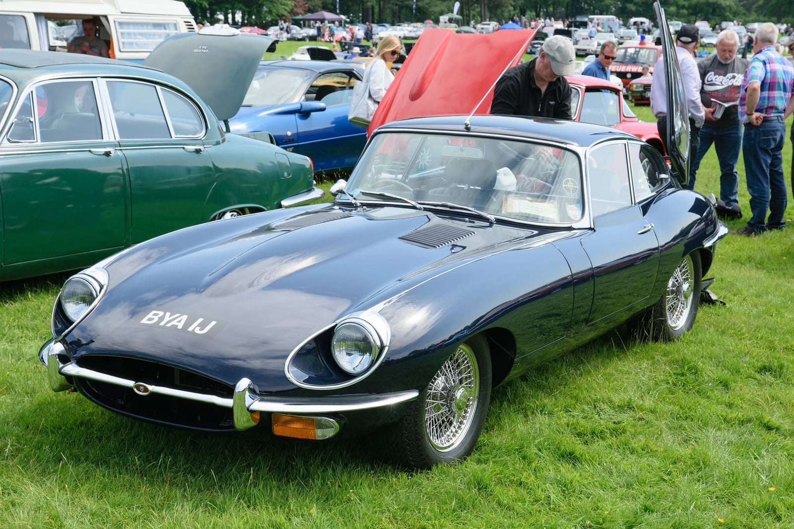 A dark blue 1970 Jaguar E-Type Series 2 coupe with UK registration BYA 1J at an outdoor classic car show