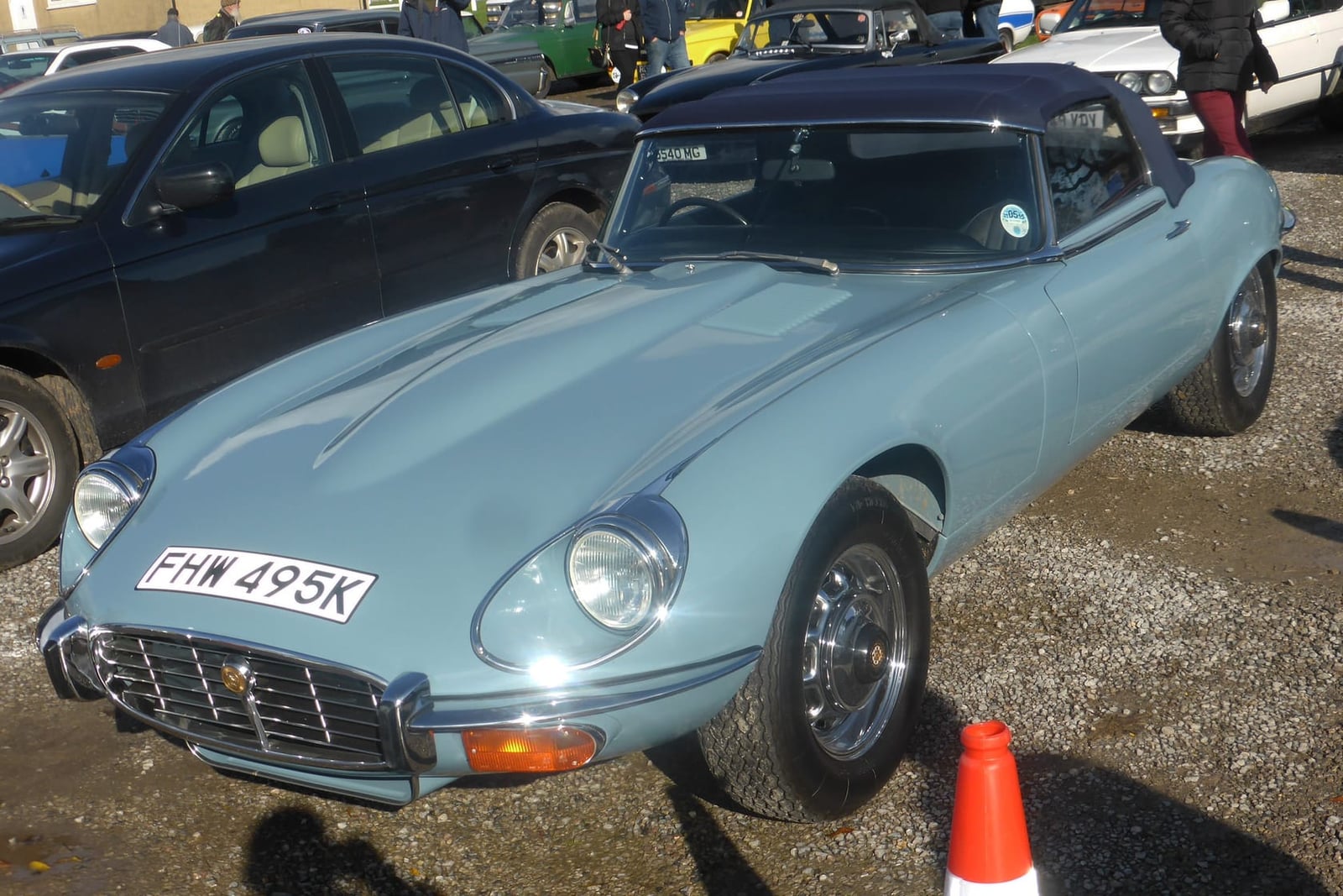 A pale blue 1972 Jaguar E-Type Series 3 V12 roadster with a UK registration and its hood up, at an outdoor show