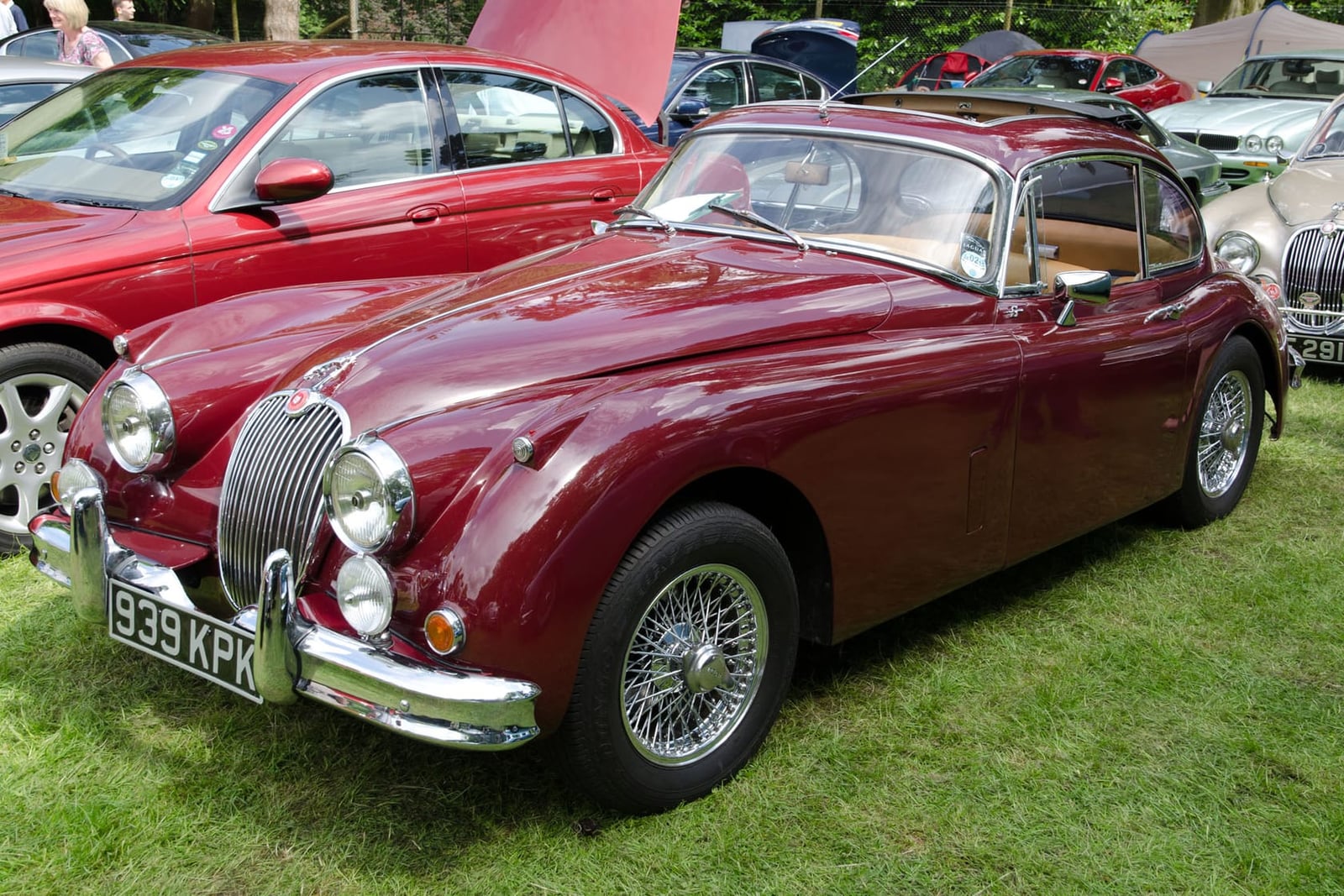 A maroon 1959 Jaguar XK150 S fixed-head coupé with wire wheels and a UK registration on a show field
