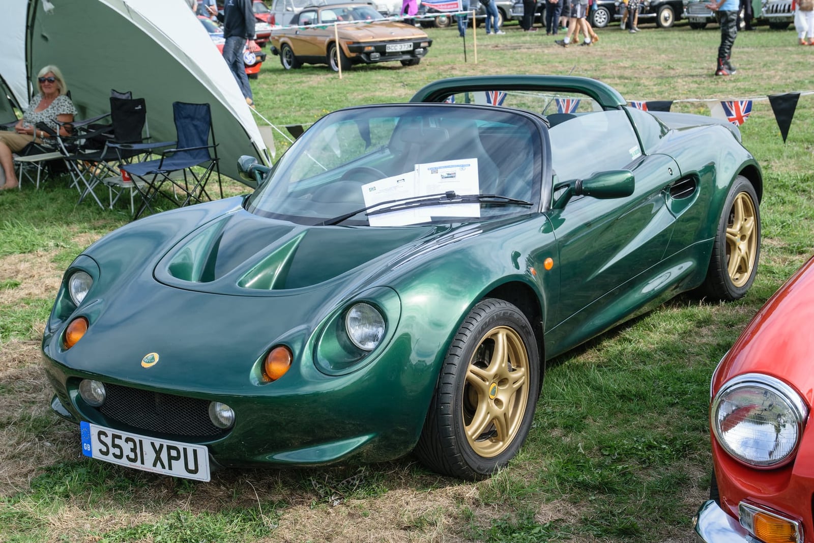 A British Racing Green 1998 Lotus Elise S1 with gold wheels and a UK registration on a show field