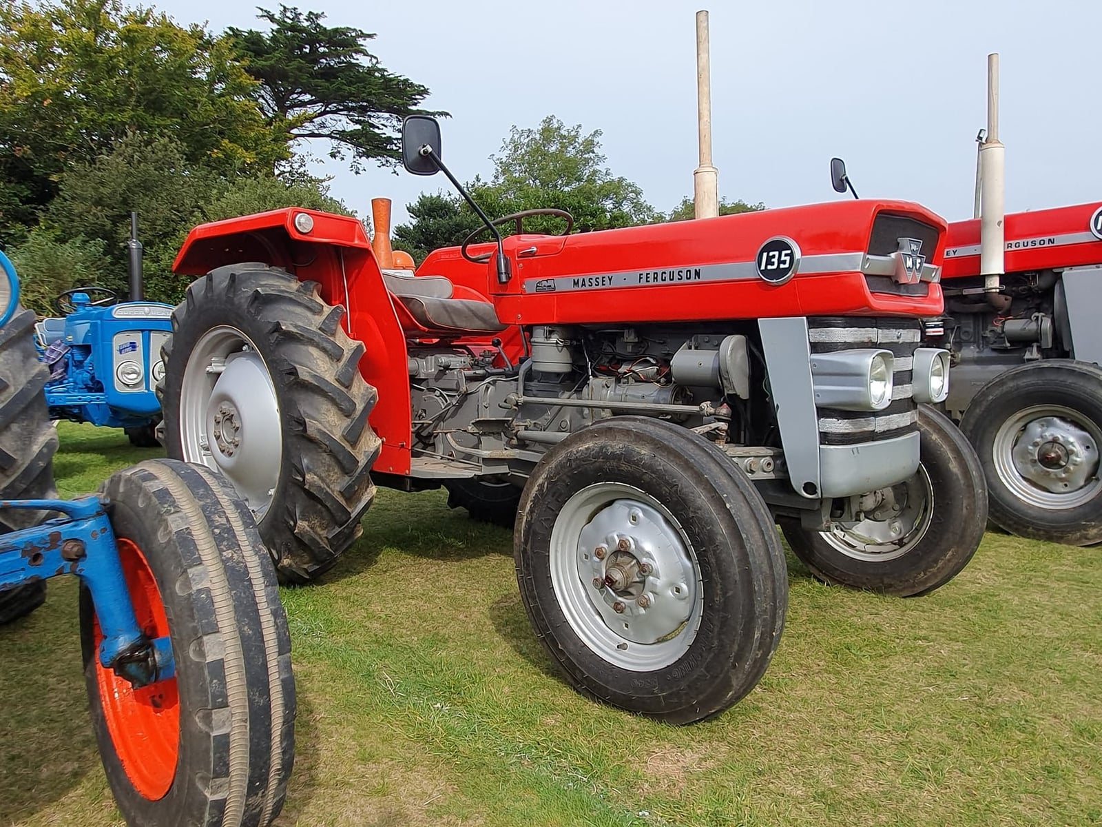 A red Massey Ferguson 135 at a Cornish vintage rally, front three-quarter view