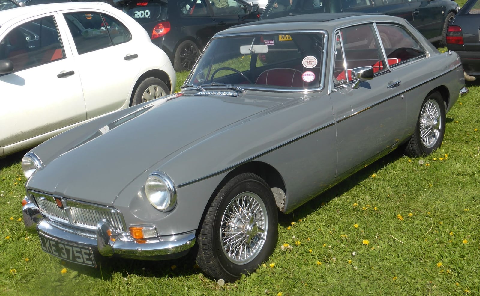 A grey 1967 MGB GT with chrome wire wheels and a UK registration on a show field